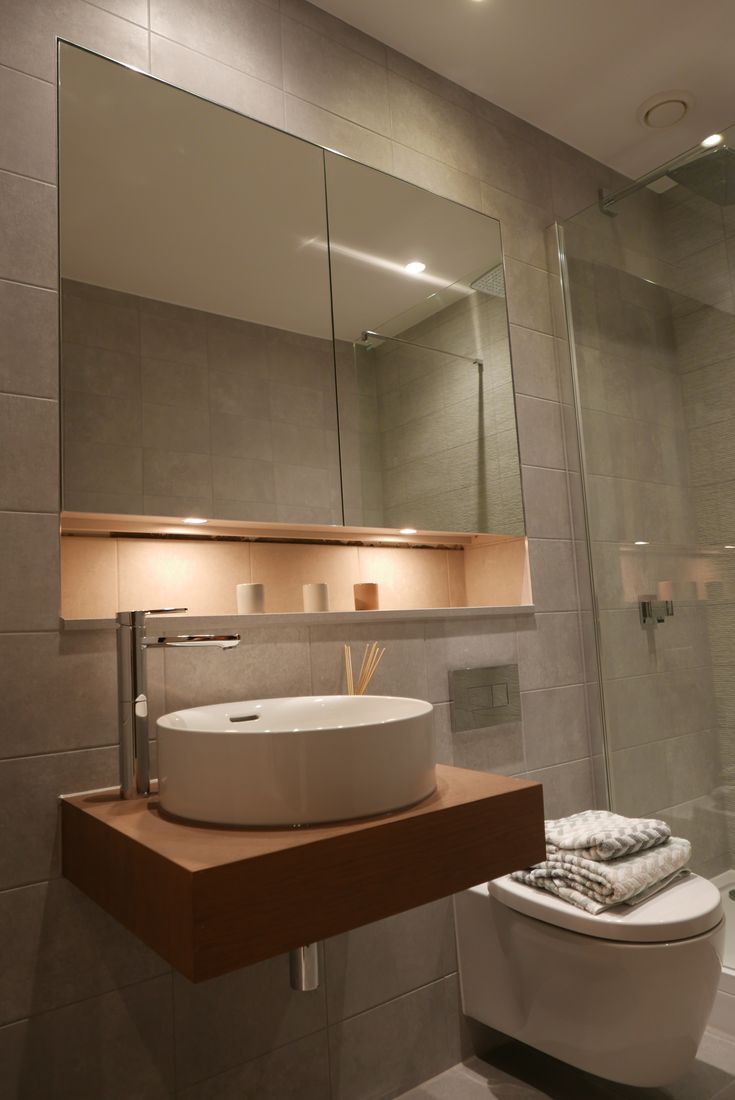 a bathroom with a toilet, sink and mirror in it's corner area next to a walk in shower