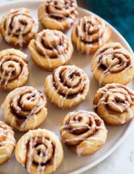 a white plate topped with cinnamon rolls covered in icing