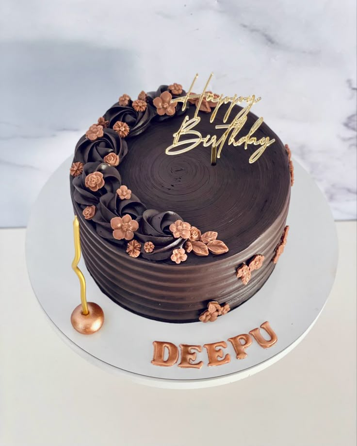 a birthday cake with chocolate frosting and flowers on the top that says happy birthday deepu