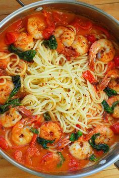 pasta with shrimp, spinach and tomato sauce in a pan on a wooden table