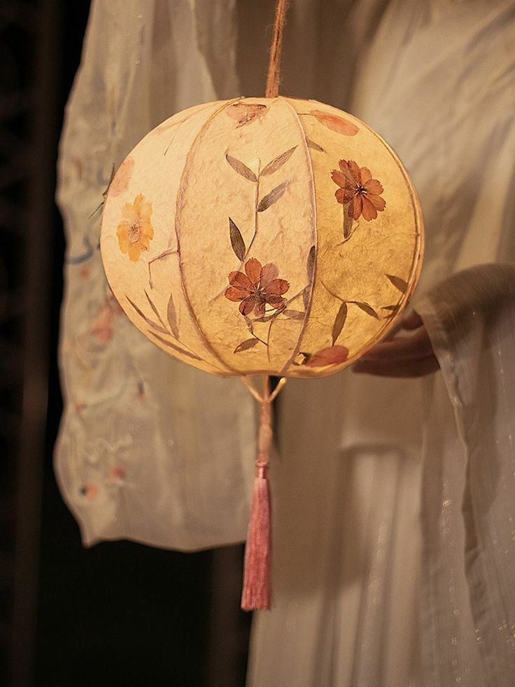 a paper lantern hanging from a string with flowers on it