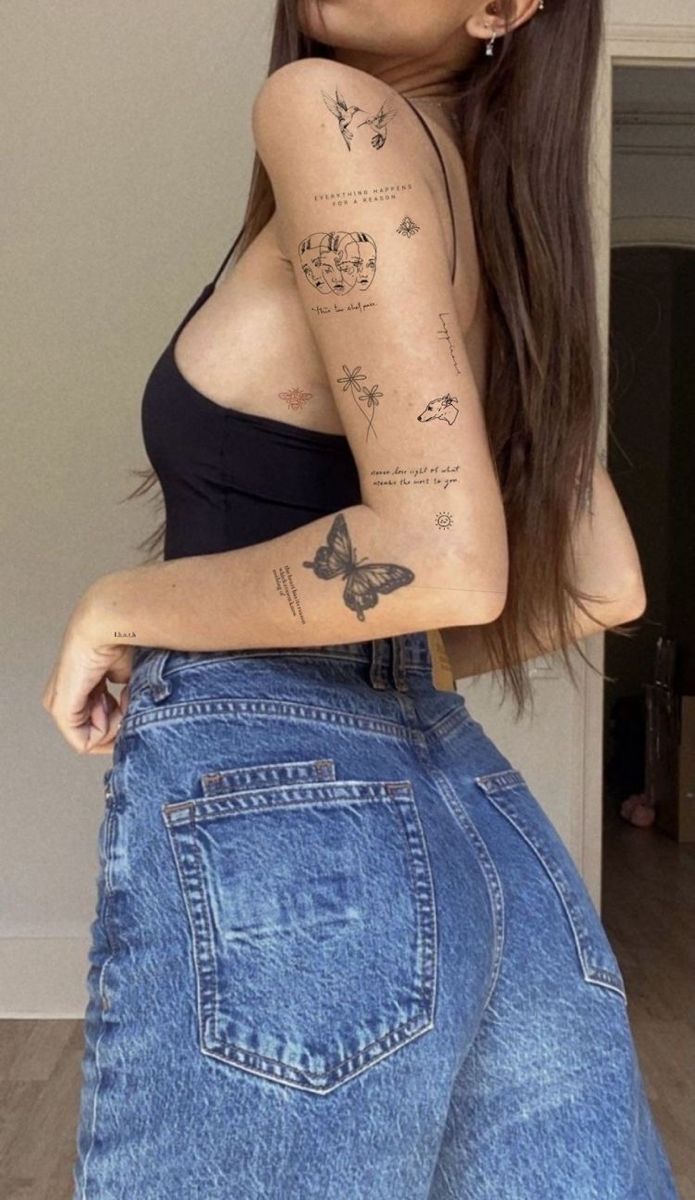 a woman with tattoos on her arm and leg, posing for the camera in jeans