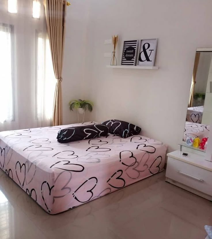 a bed room with a neatly made bed next to a dresser and mirror on the wall