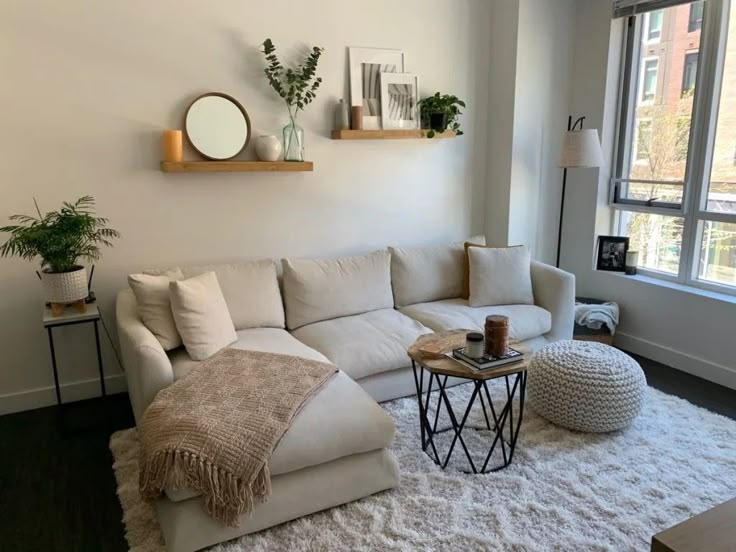 a living room with a white couch and two round tables in front of a large window