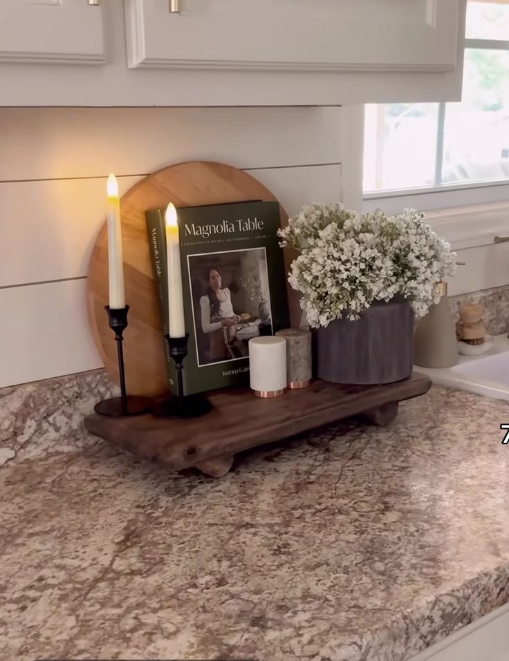 a kitchen counter top with candles and flowers on it