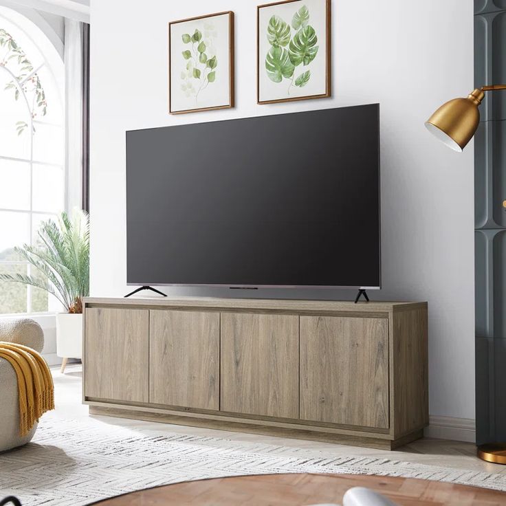 a flat screen tv sitting on top of a wooden entertainment center in a living room