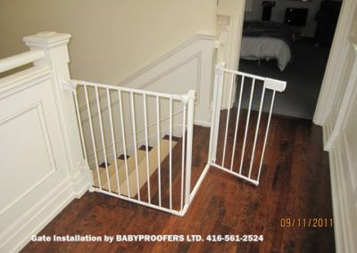 two white baby gates in the corner of a room next to a bed and wooden floor