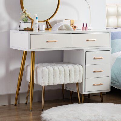 a white vanity with gold legs and mirror on the wall next to a blue bed