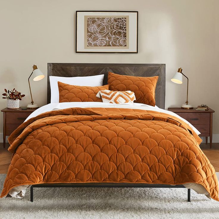 a bed with an orange comforter and pillows