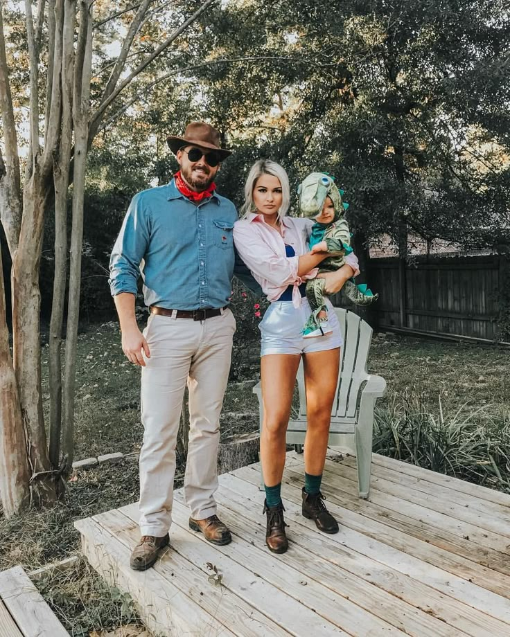 a man standing next to a woman holding a baby on top of a wooden deck