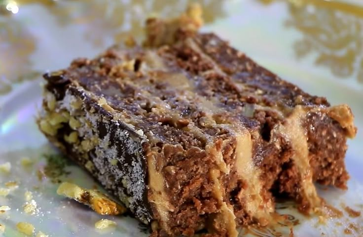 a piece of cake sitting on top of a white and gold plate covered in nuts