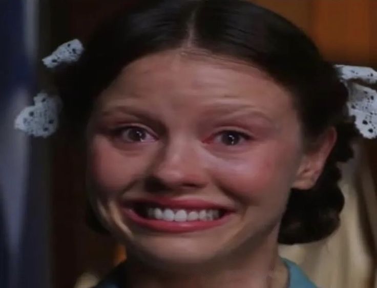 a woman with tears on her face and hair is smiling at the camera while wearing a green shirt