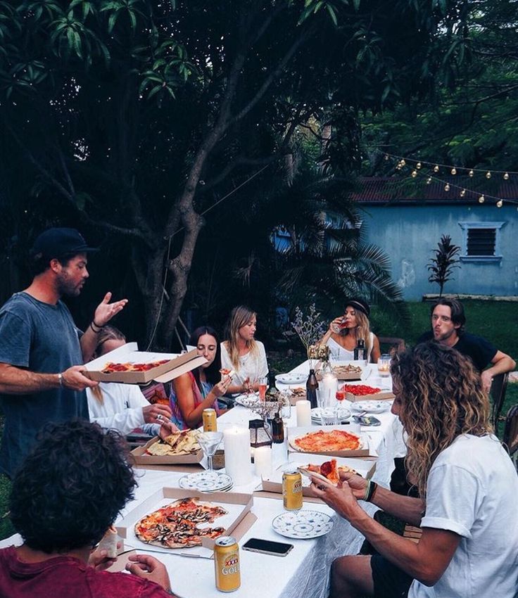 a group of people sitting around a table eating pizza