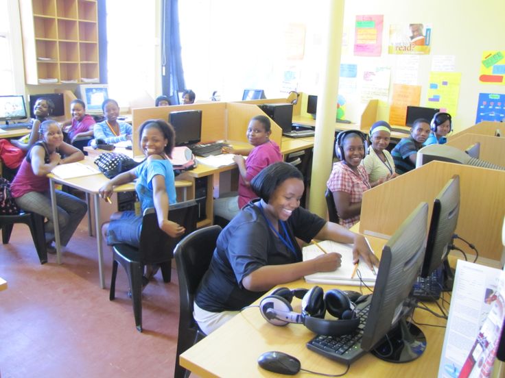 a group of people sitting at desks in a classroom with computers on the desk