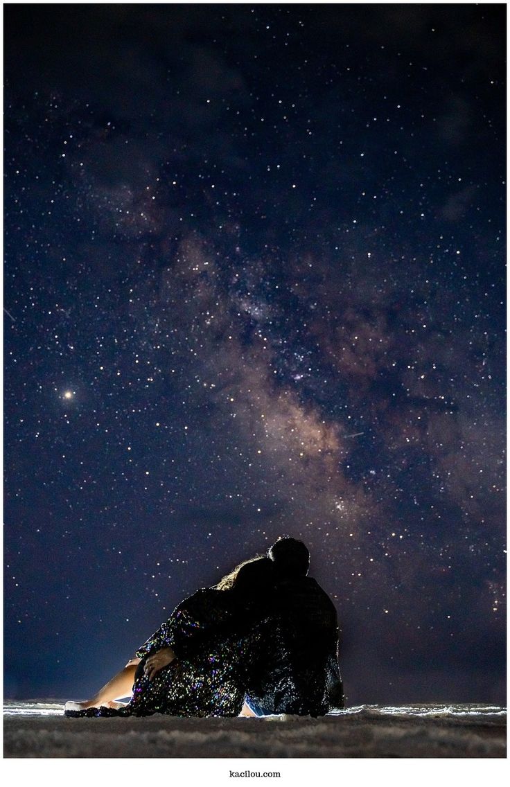 two people are sitting under the stars in the sky