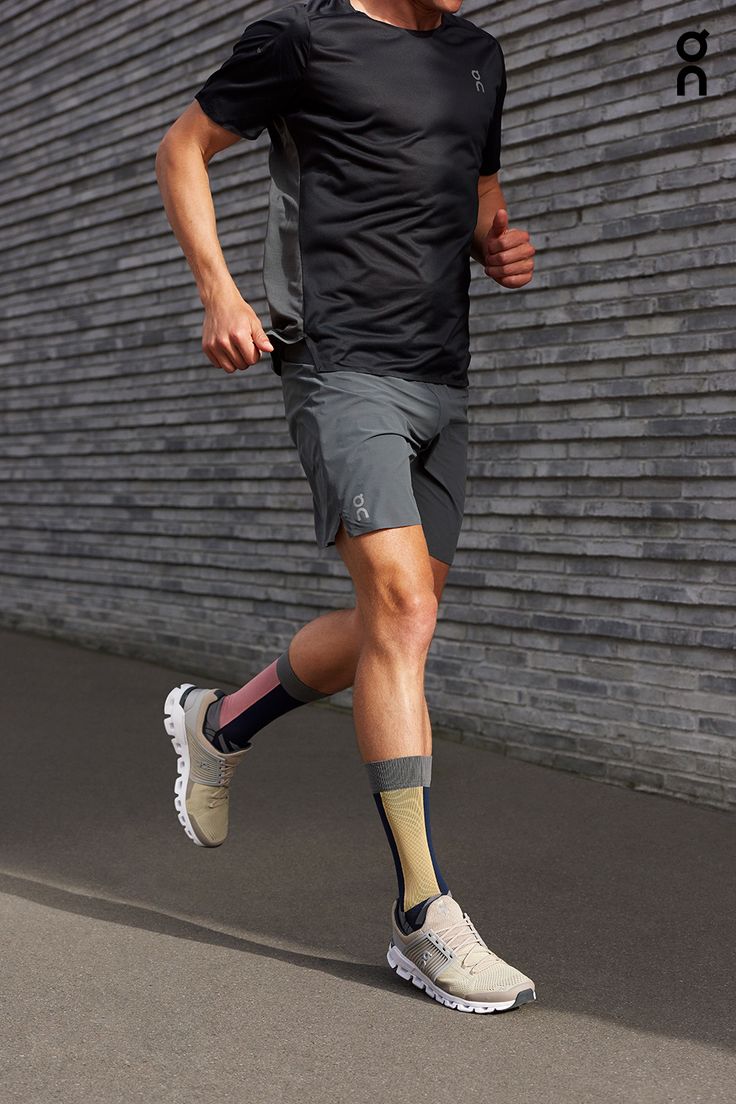 a man running in front of a brick wall with his foot on the ground while wearing socks