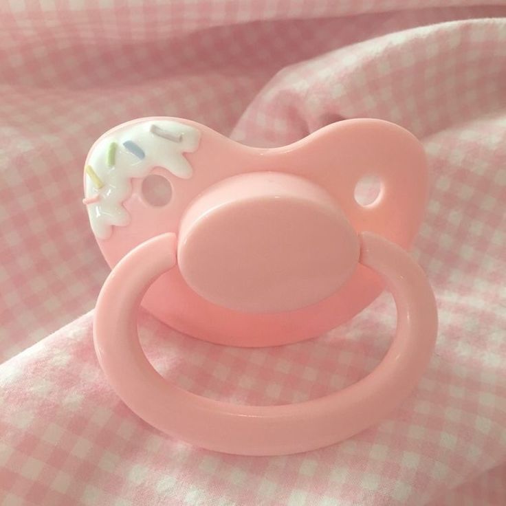 a pink pacifier sitting on top of a checkered blanket in the bedding