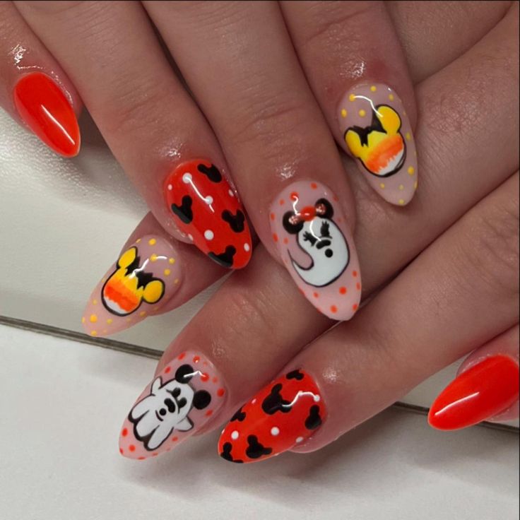 a woman's hand with mickey mouse nail art on her nails and an orange manicure