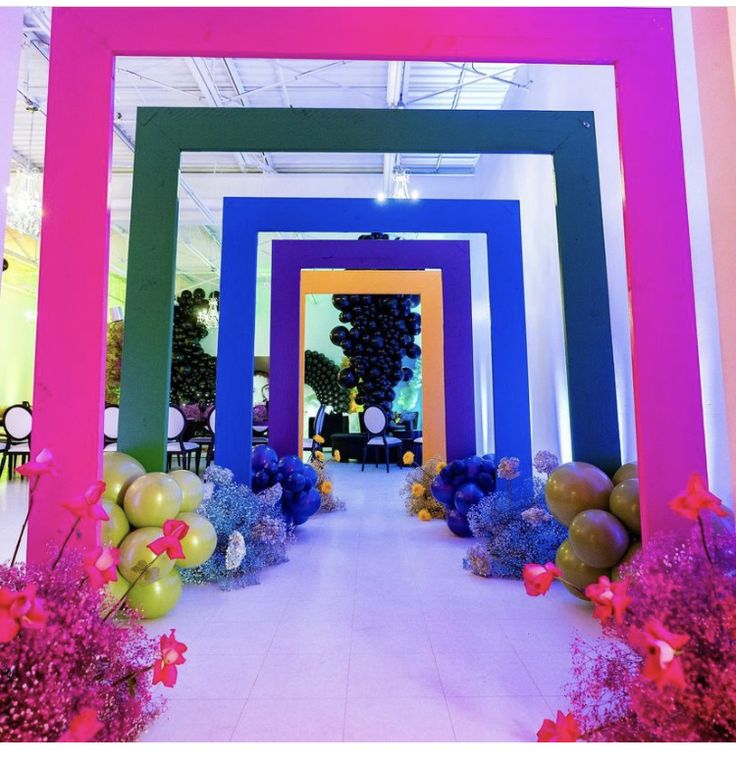 the entrance to an art gallery decorated with balloons and flowers in purple, blue, green, yellow and pink colors