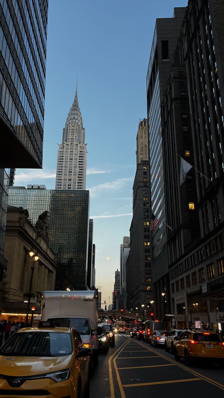 cars are driving down the street in front of tall buildings with skyscrapers on either side