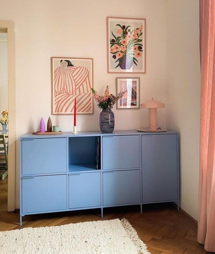 a blue cabinet in a room with pictures on the wall above it and a white rug