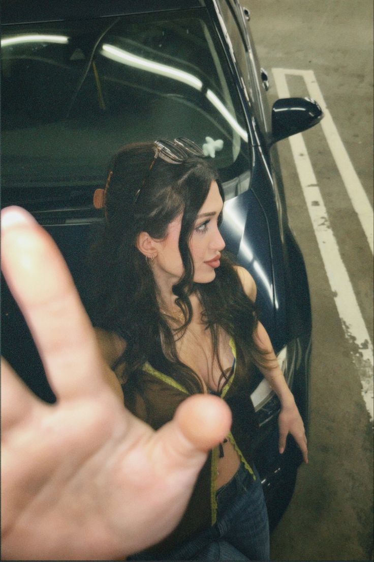 a woman sitting in the back of a car holding her hand up