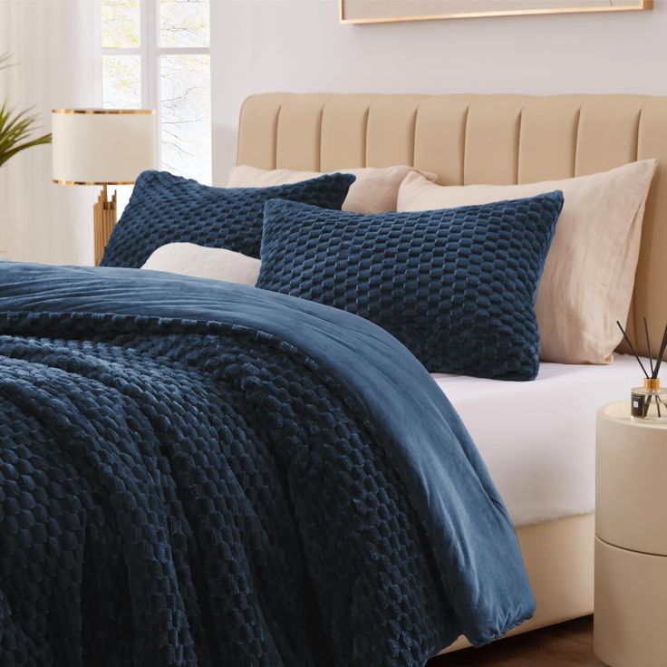 a bed with blue comforters and pillows in a bedroom