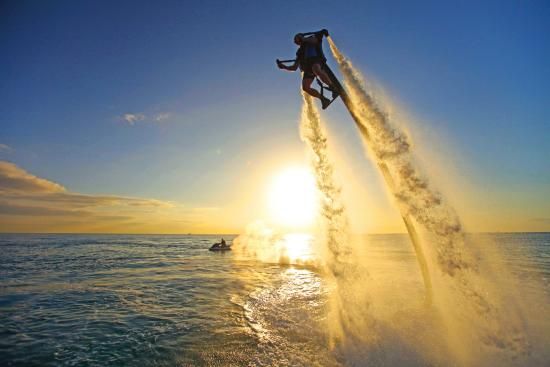 a person on a jet ski jumping in the air over the water with another boat behind them