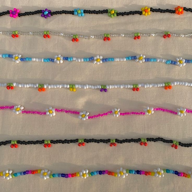 multicolored beaded bracelets are lined up on a white tablecloth,