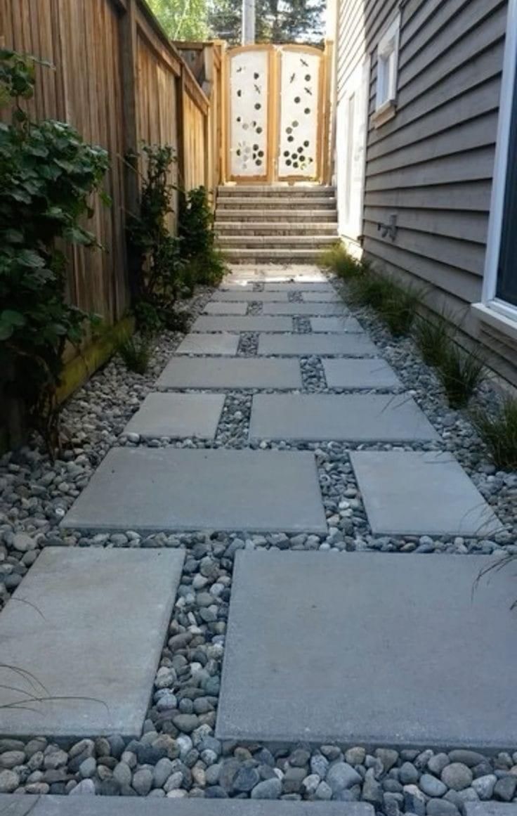 a walkway made out of stones and gravel with a wooden fence in the back ground