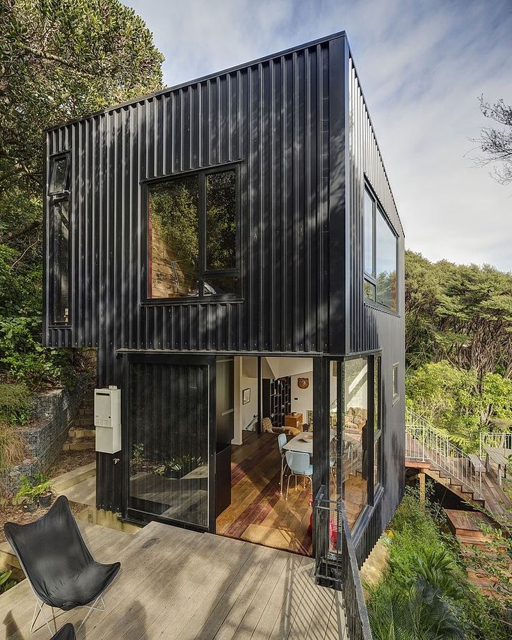 a house made out of shipping containers on the side of a hill with trees in the background