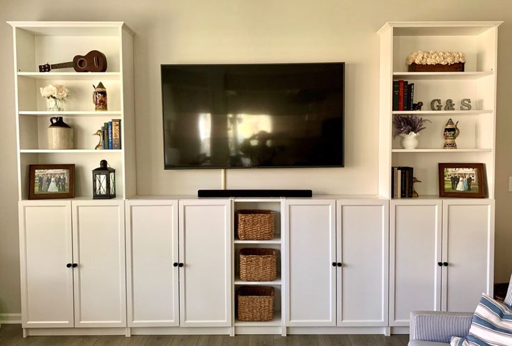 a flat screen tv mounted to the side of a wall next to white bookcases