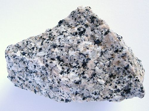 a rock with black and white speckles sitting on top of a white surface