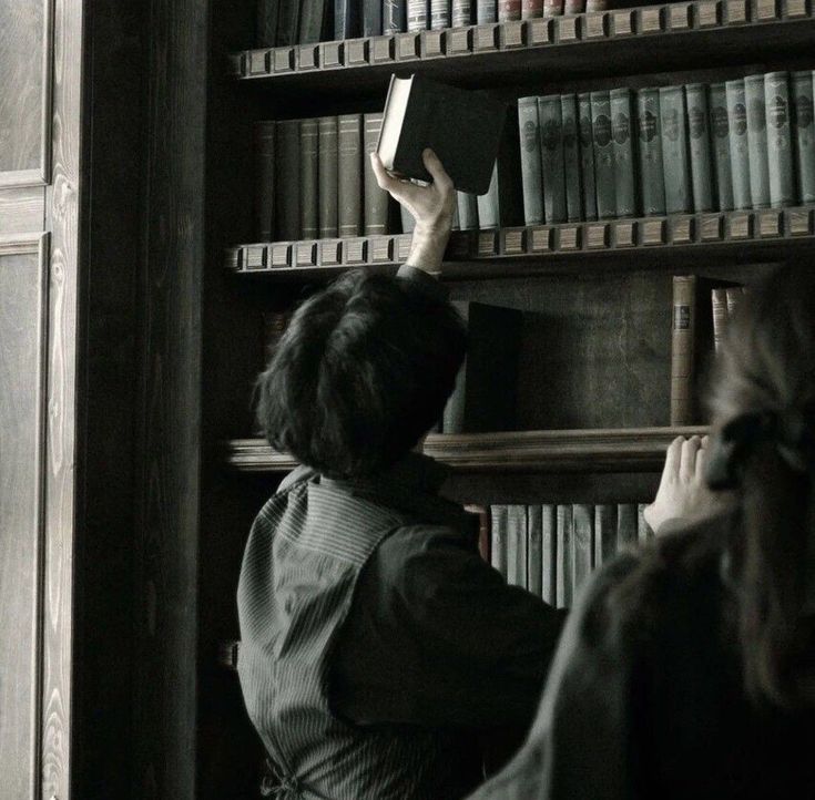 a woman is reading a book in front of a bookshelf