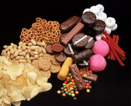 an assortment of snacks including cookies, crackers and candies on a black background