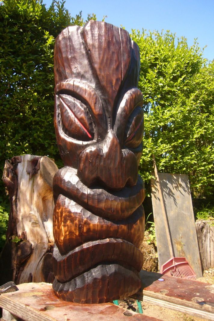 a wooden statue sitting on top of a table next to some trees and other items