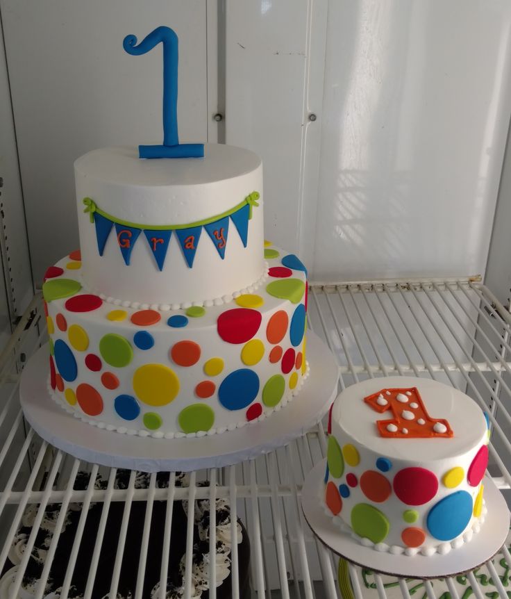 two colorful birthday cakes sitting on top of a metal rack in front of a door