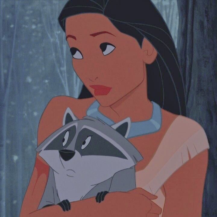 a woman holding a raccoon in the woods