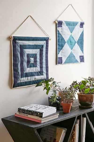 two quilted wall hangings with plants and books