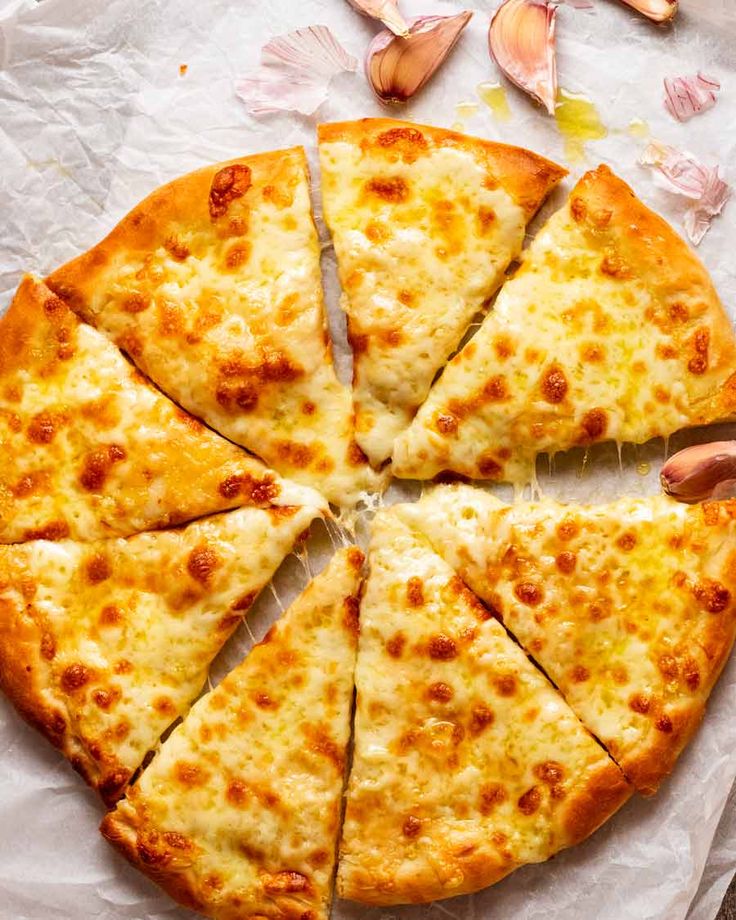 a sliced pizza sitting on top of a piece of paper next to garlic and flowers