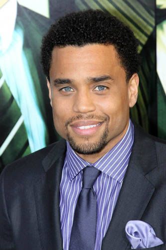 a close up of a person wearing a suit and tie with a smile on his face