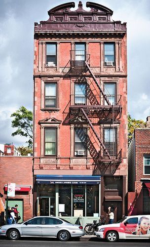 cars are parked in front of an old brick building with fire escapes on the roof