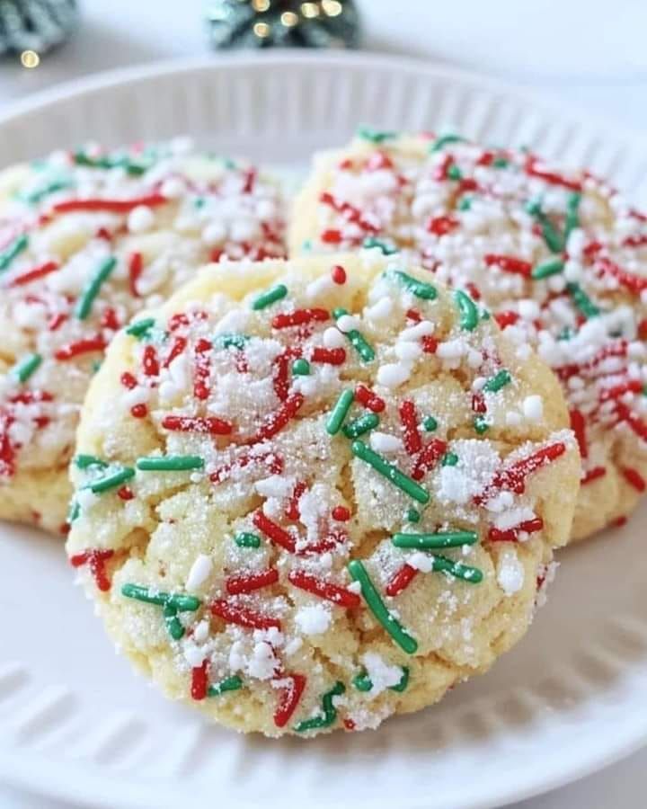 three sugar cookies with sprinkles on a white plate