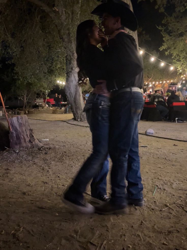 a man and woman embracing under a tree at night