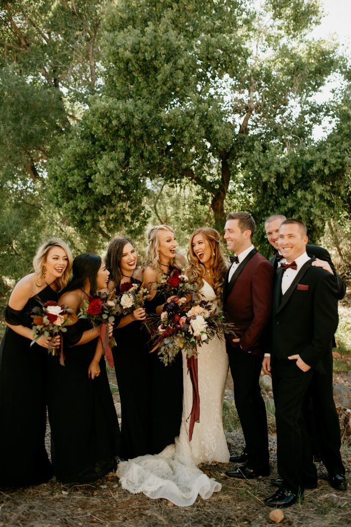 a group of people standing next to each other in front of some trees and bushes