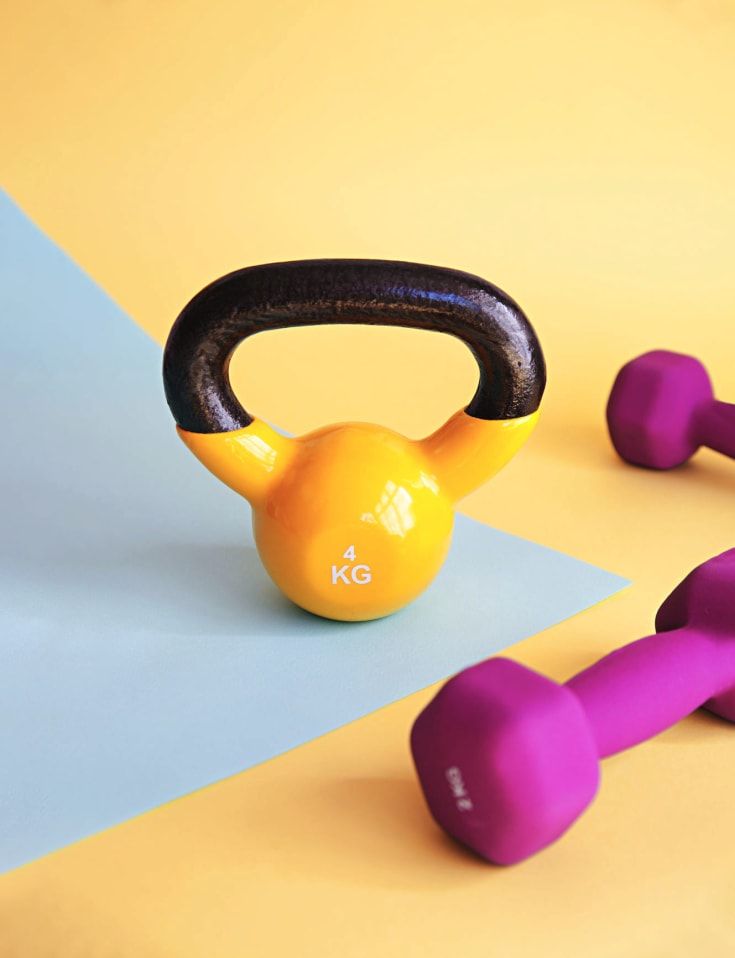 an orange and purple kettle sitting on top of a blue mat next to two pink dumbs