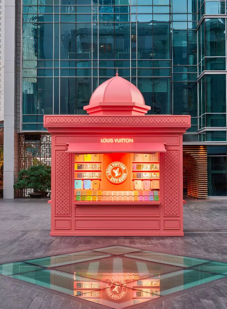 an orange kiosk sitting in the middle of a plaza