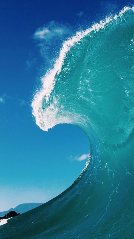 a man riding a wave on top of a surfboard in the ocean under a blue sky