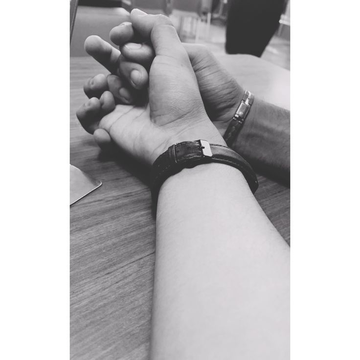 two people holding hands while sitting at a table with their arm wrapped around each other