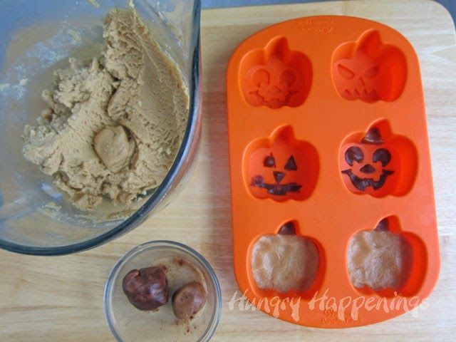 an orange tray filled with halloween treats next to a cupcake molder and bowl